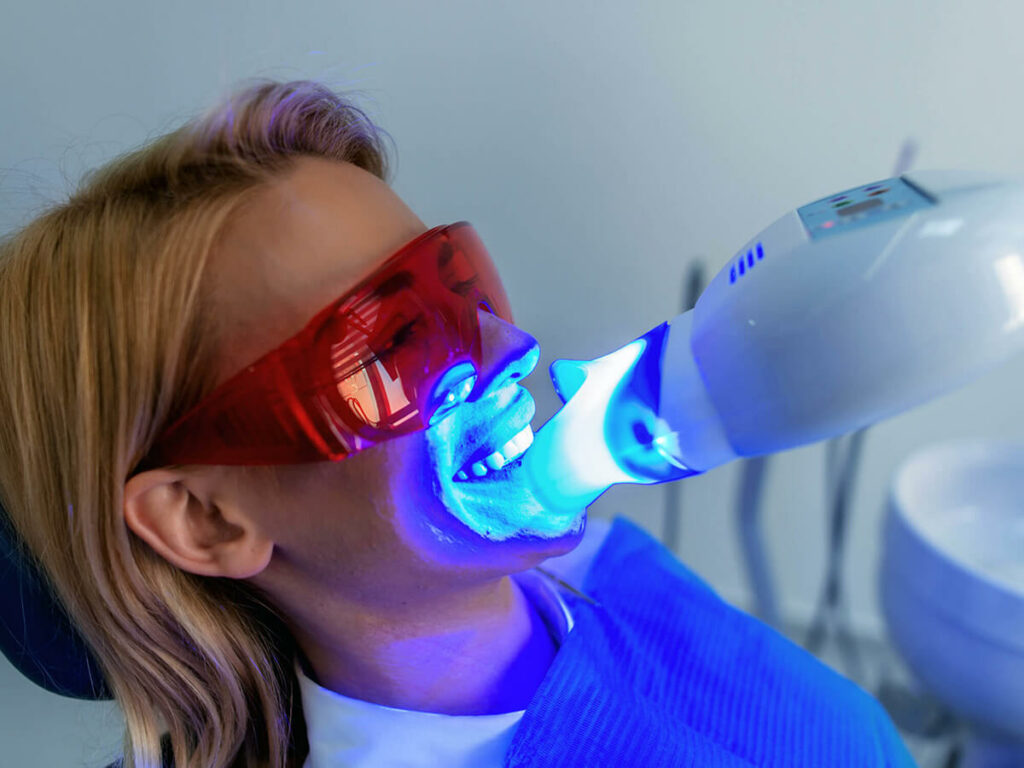 Woman receiving a light activated teeth whitening treatment